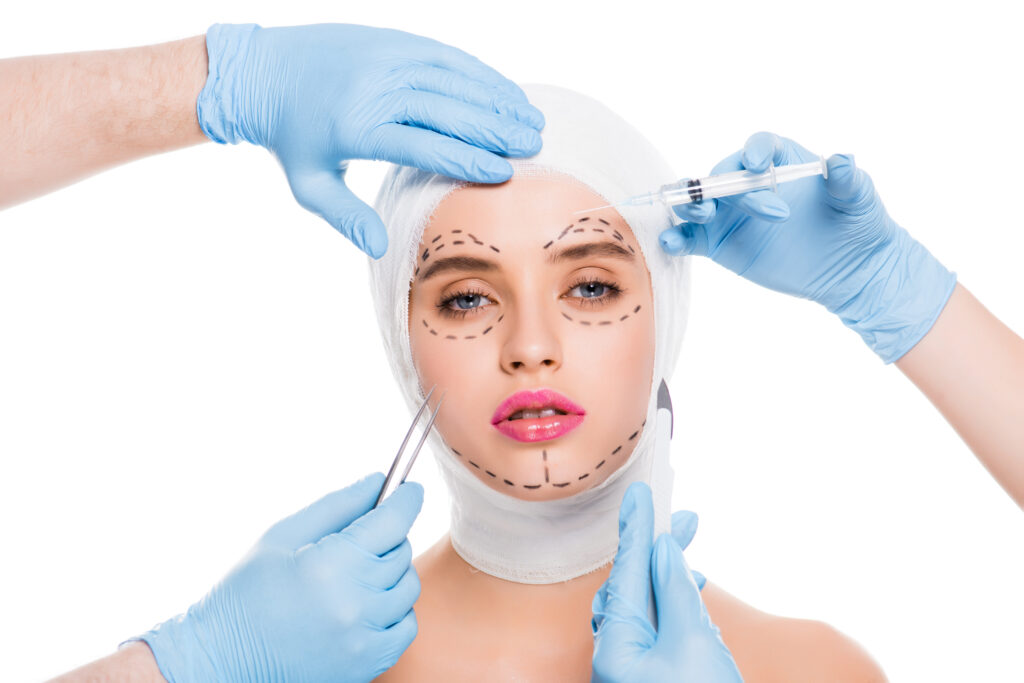 cropped view of plastic surgeons in blue latex gloves with medical equipment near face of woman with